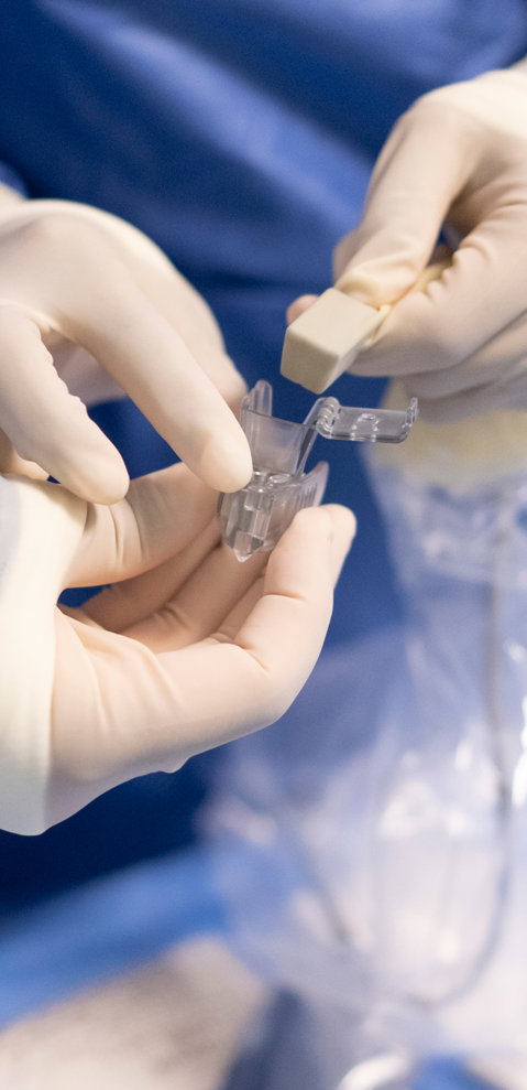 The gloved hands of two interventional radiologists handling medical equipment